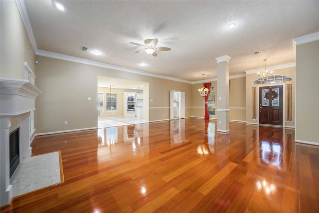 unfurnished living room with ceiling fan with notable chandelier, a textured ceiling, hardwood / wood-style floors, and crown molding