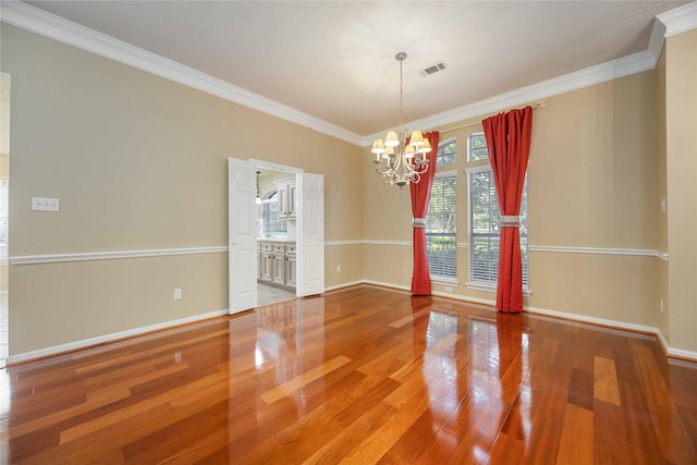 spare room featuring wood-type flooring, a chandelier, and crown molding