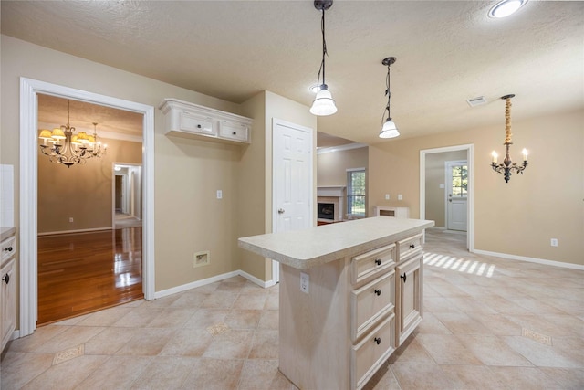 kitchen with a textured ceiling, decorative light fixtures, light tile patterned floors, a kitchen island, and an inviting chandelier