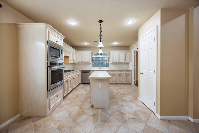 kitchen with a kitchen island, visible vents, light countertops, appliances with stainless steel finishes, and pendant lighting