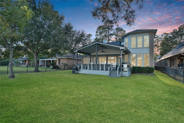 back house at dusk featuring a yard and ceiling fan