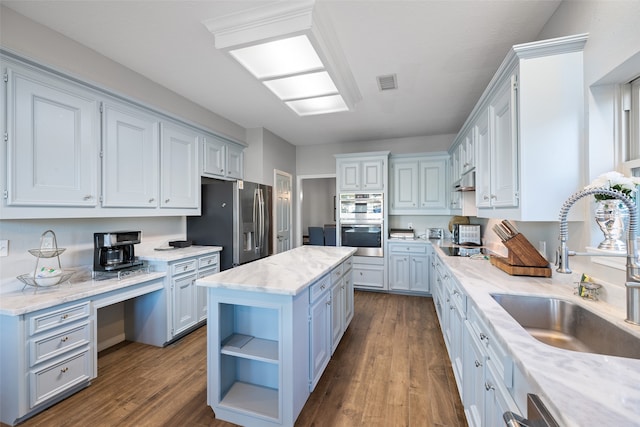 kitchen featuring dark wood-type flooring, stainless steel appliances, sink, a center island, and white cabinets