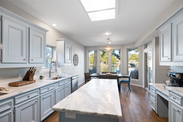 kitchen with a kitchen island, dark hardwood / wood-style floors, sink, decorative light fixtures, and stainless steel dishwasher