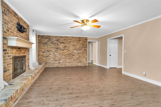 unfurnished living room featuring ceiling fan, hardwood / wood-style flooring, a brick fireplace, ornamental molding, and brick wall