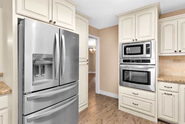 kitchen featuring light hardwood / wood-style flooring, cream cabinets, stainless steel appliances, and light stone counters