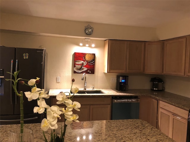 kitchen with light stone countertops, stainless steel dishwasher, sink, and black fridge with ice dispenser