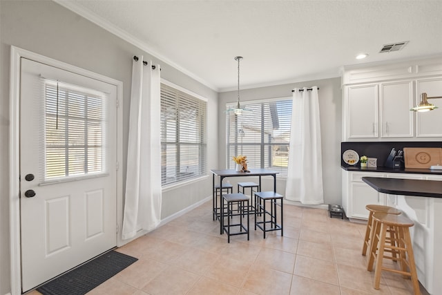 tiled dining space with ornamental molding and plenty of natural light