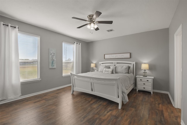 bedroom with ceiling fan, multiple windows, and dark hardwood / wood-style flooring