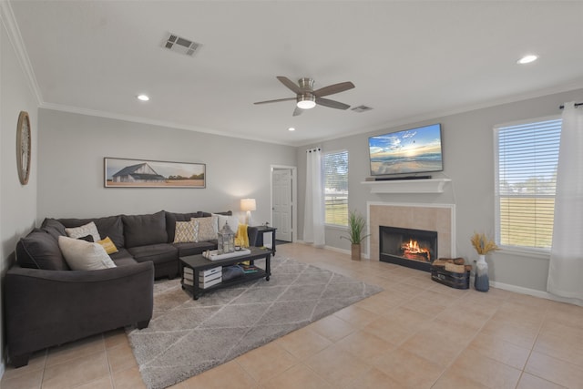 living room with ceiling fan, ornamental molding, light tile patterned floors, and a tile fireplace