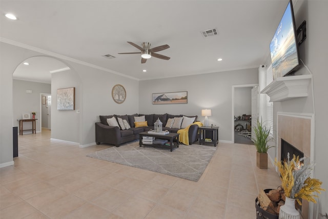 tiled living room with crown molding, a fireplace, and ceiling fan