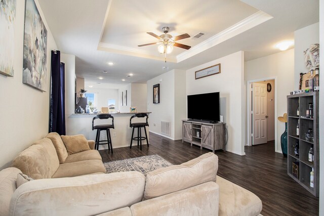 living room featuring dark hardwood / wood-style floors, a tray ceiling, and ceiling fan