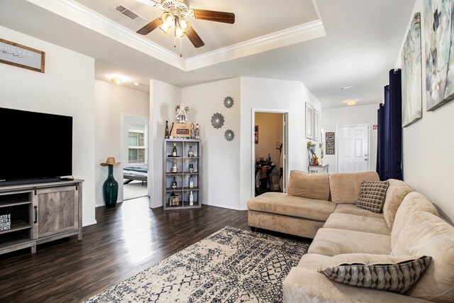 living room with ornamental molding, dark hardwood / wood-style floors, a tray ceiling, and ceiling fan