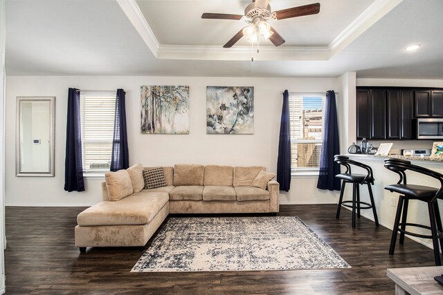 living room featuring crown molding, dark hardwood / wood-style floors, a tray ceiling, and ceiling fan