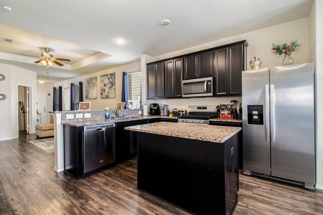 kitchen featuring ceiling fan, appliances with stainless steel finishes, a center island, and dark hardwood / wood-style flooring