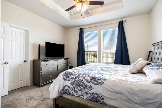 carpeted bedroom featuring ceiling fan, crown molding, and a tray ceiling