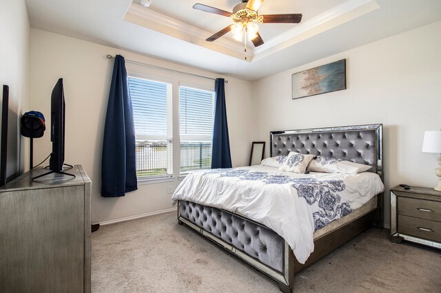 bedroom with ornamental molding, light colored carpet, a raised ceiling, and ceiling fan