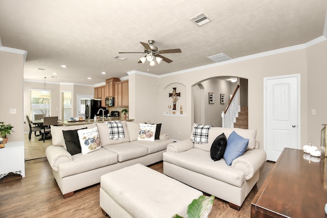 living room with ceiling fan, wood-type flooring, and ornamental molding