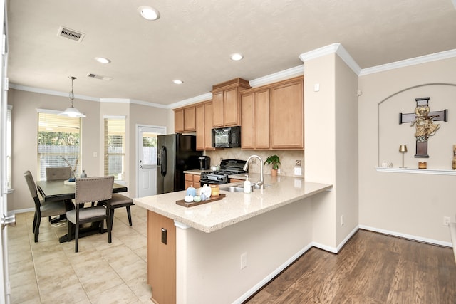 kitchen featuring kitchen peninsula, light hardwood / wood-style flooring, ornamental molding, black appliances, and decorative light fixtures