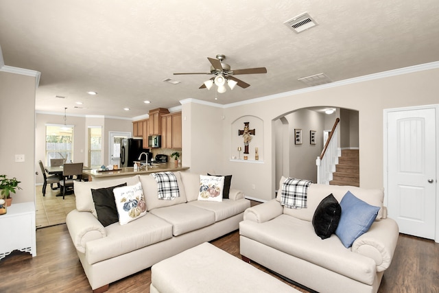 living room with sink, dark wood-type flooring, crown molding, and ceiling fan