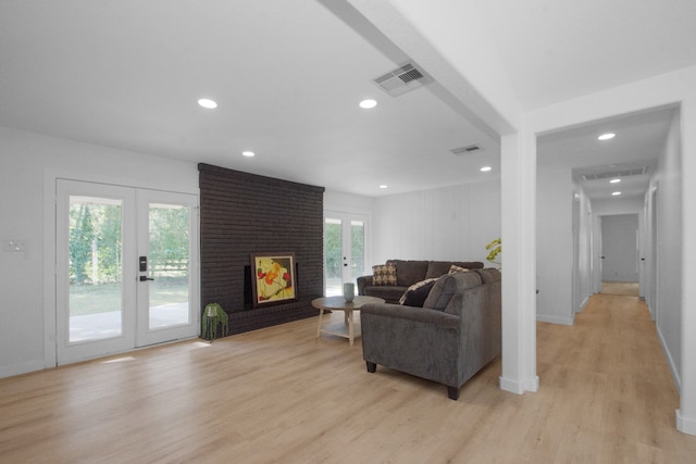 living room featuring french doors, light hardwood / wood-style flooring, plenty of natural light, and a brick fireplace