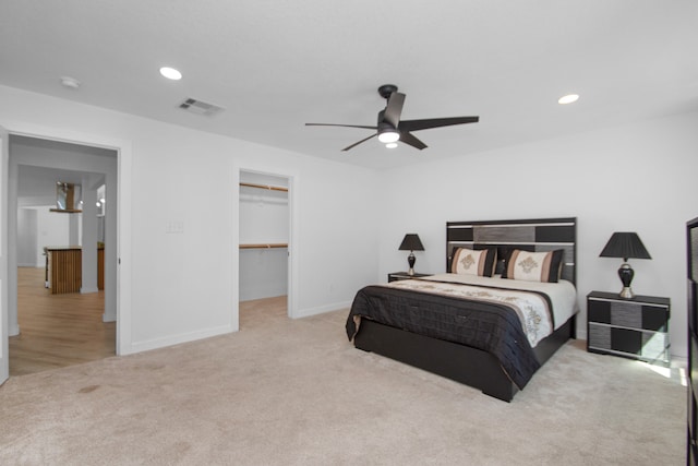 bedroom with a closet, light colored carpet, a spacious closet, and ceiling fan