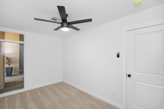 carpeted empty room with ceiling fan and a brick fireplace