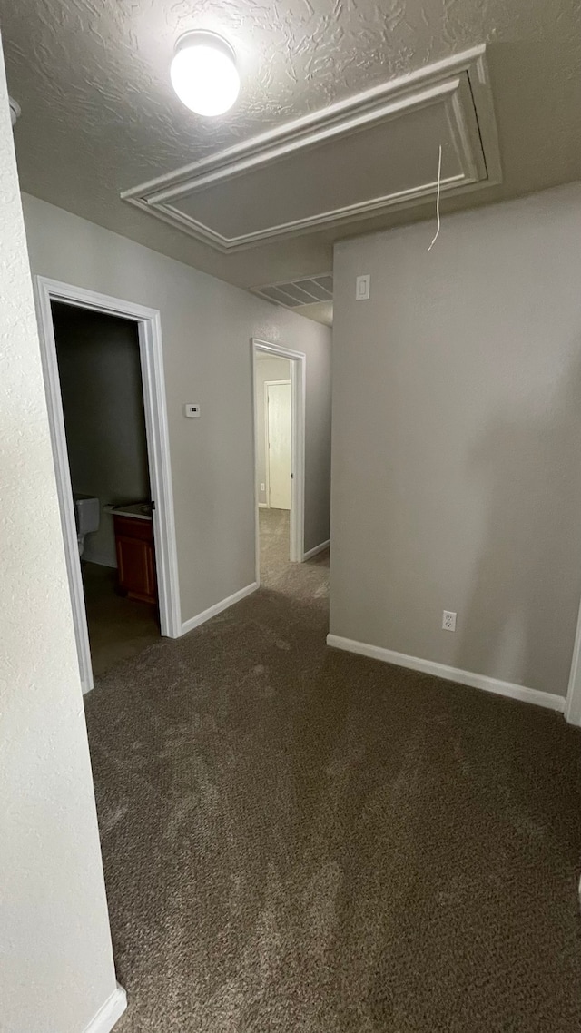 unfurnished room featuring a textured ceiling and dark carpet