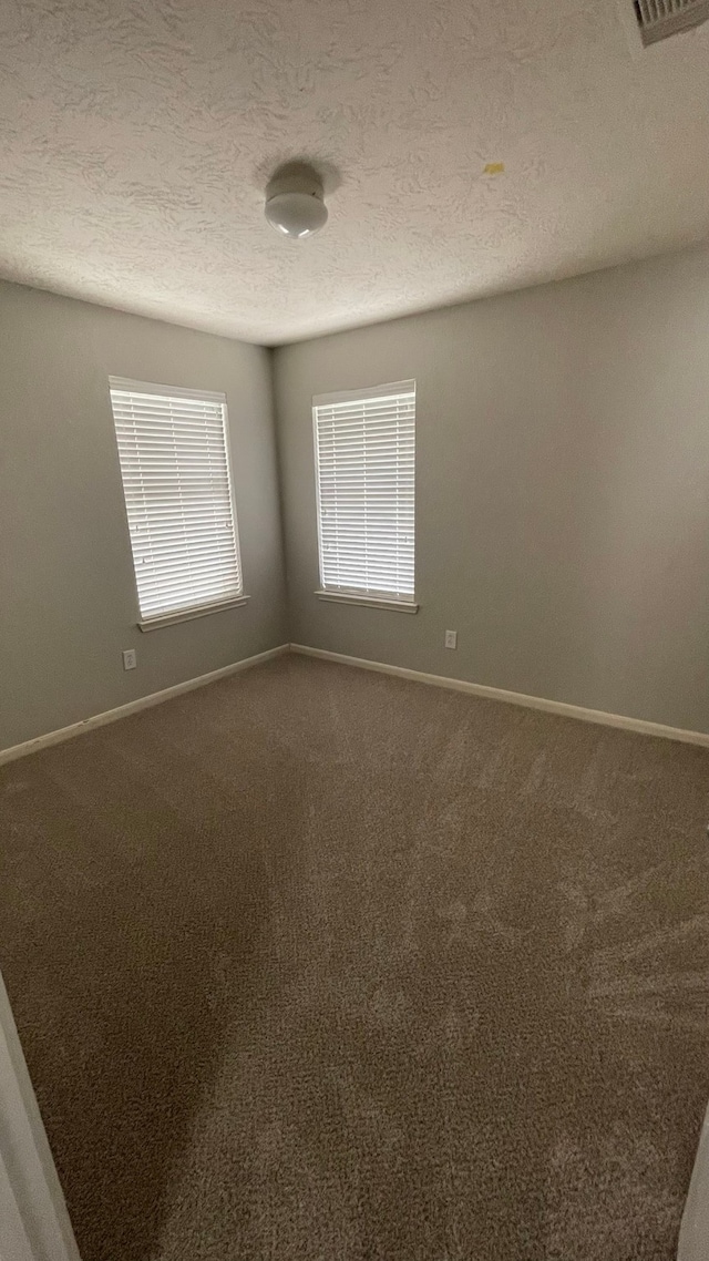 carpeted spare room with a textured ceiling