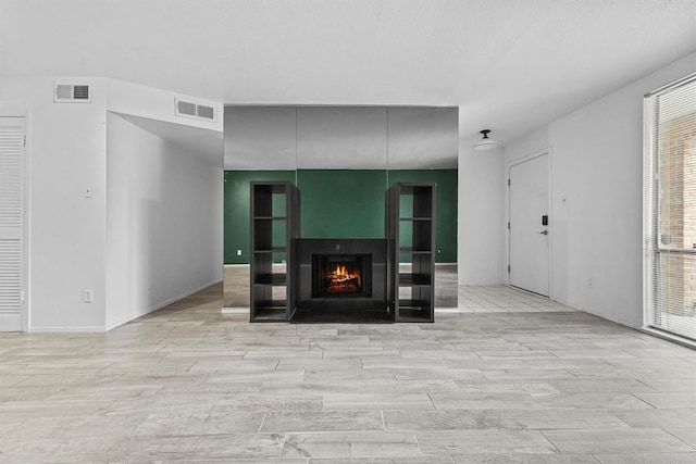 4643 Wild Indigo Unit 414, Houston, TX 77027 - unfurnished living room featuring visible vents, wood finished floors, and a lit fireplace