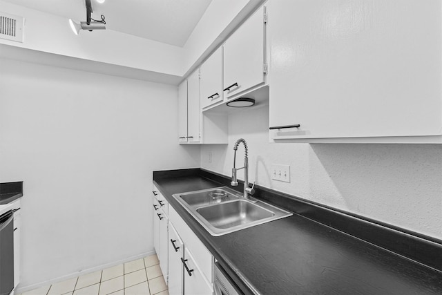 kitchen with track lighting, sink, white cabinetry, stainless steel dishwasher, and light tile patterned floors