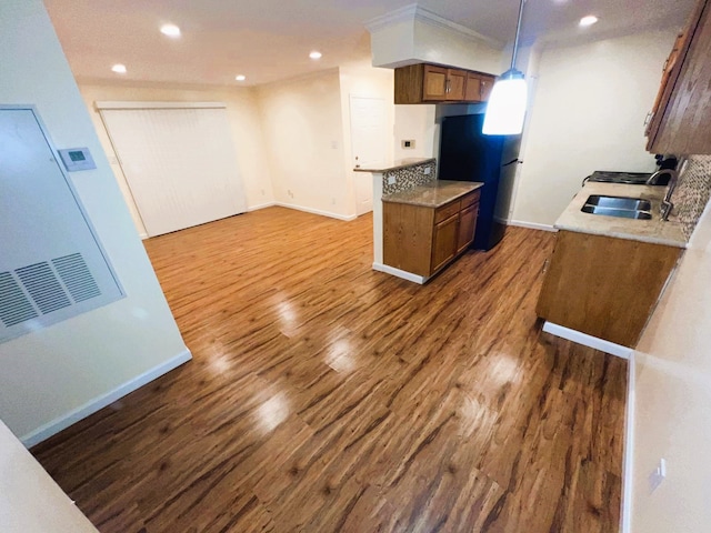 kitchen with dark wood-type flooring, hanging light fixtures, sink, and black refrigerator