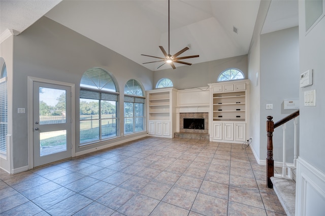 unfurnished living room featuring light tile patterned floors, ceiling fan, high vaulted ceiling, a fireplace, and built in features