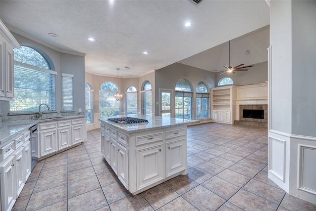 kitchen featuring appliances with stainless steel finishes, ceiling fan with notable chandelier, a center island, hanging light fixtures, and white cabinets