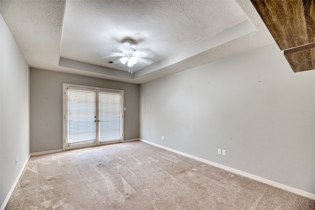 carpeted empty room featuring ceiling fan, a raised ceiling, and a textured ceiling