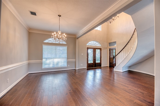 foyer entrance with french doors, dark wood-type flooring, crown molding, a notable chandelier, and a textured ceiling