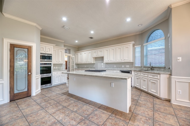 kitchen featuring a kitchen island, white cabinets, light stone counters, and stainless steel appliances