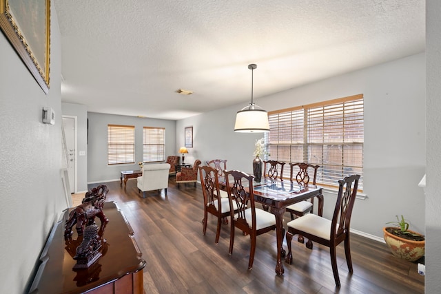 dining space with a textured ceiling and dark hardwood / wood-style floors