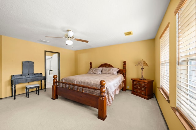 bedroom with ceiling fan, a textured ceiling, multiple windows, and light colored carpet