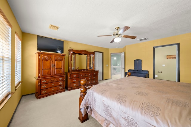 carpeted bedroom with connected bathroom, ceiling fan, a textured ceiling, and multiple windows