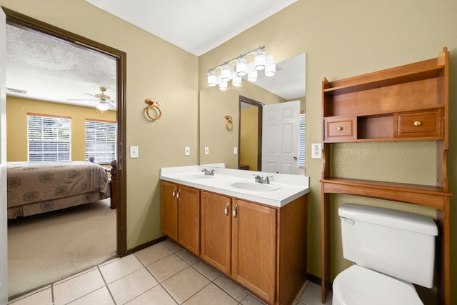 bathroom with ceiling fan, a textured ceiling, toilet, vanity, and tile patterned floors