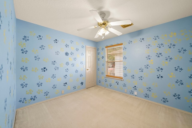 spare room featuring ceiling fan, light carpet, and a textured ceiling