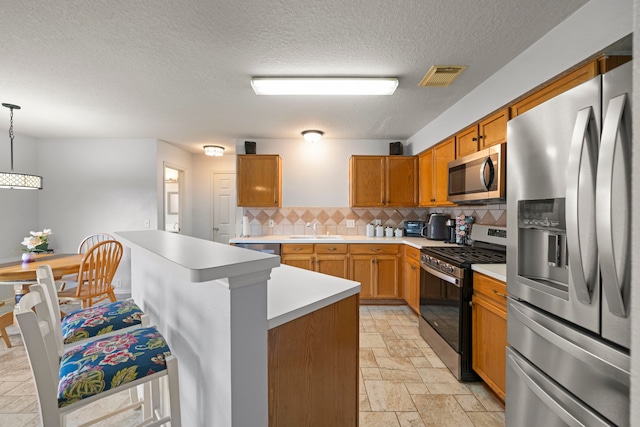 kitchen featuring appliances with stainless steel finishes, sink, a kitchen breakfast bar, decorative light fixtures, and decorative backsplash