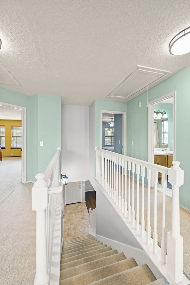 stairs featuring carpet floors and a textured ceiling