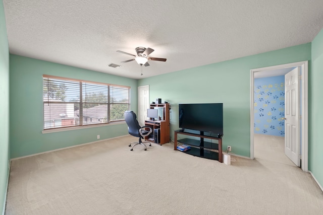 office space with a textured ceiling, light colored carpet, and ceiling fan