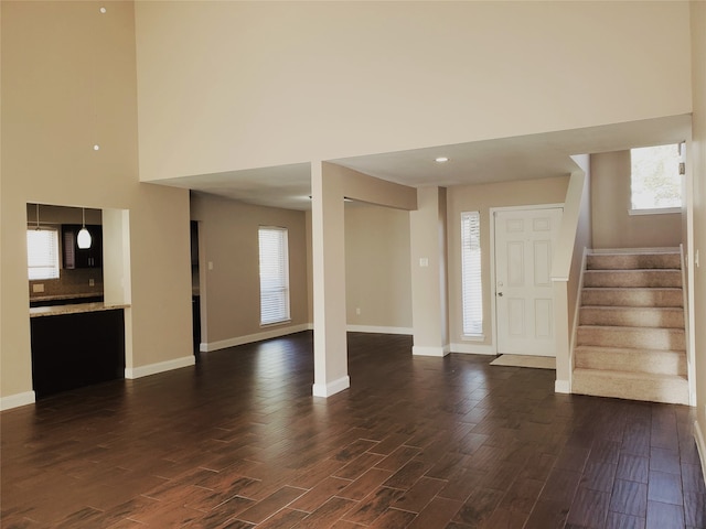 foyer entrance featuring a towering ceiling and dark hardwood / wood-style floors