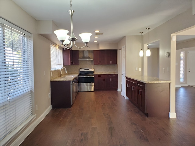 kitchen featuring kitchen peninsula, appliances with stainless steel finishes, dark hardwood / wood-style flooring, wall chimney exhaust hood, and decorative light fixtures