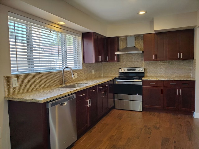 kitchen featuring appliances with stainless steel finishes, tasteful backsplash, wall chimney exhaust hood, dark wood-type flooring, and sink