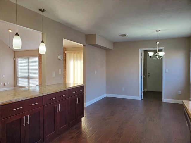 kitchen with a notable chandelier, light stone counters, dark wood-type flooring, and hanging light fixtures