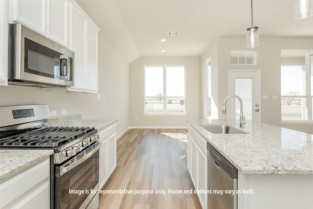 kitchen with sink, an island with sink, white cabinetry, stainless steel appliances, and light hardwood / wood-style flooring