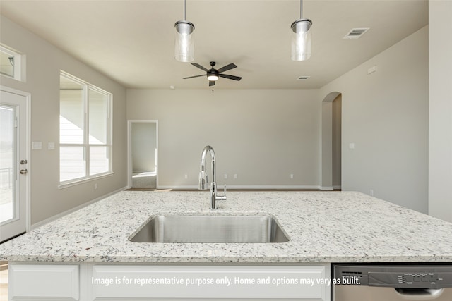 kitchen featuring light stone counters, sink, stainless steel dishwasher, and hanging light fixtures